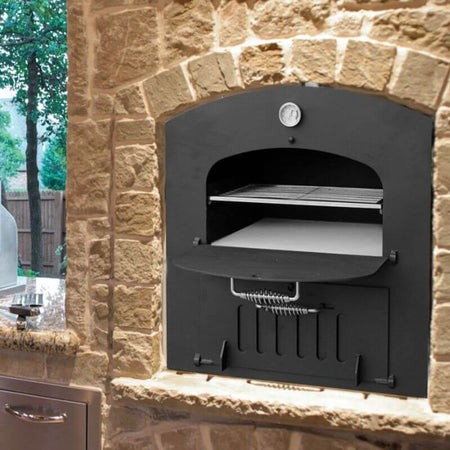 Black wood-fired oven with the door open, built into a stone enclosure of an outdoor kitchen