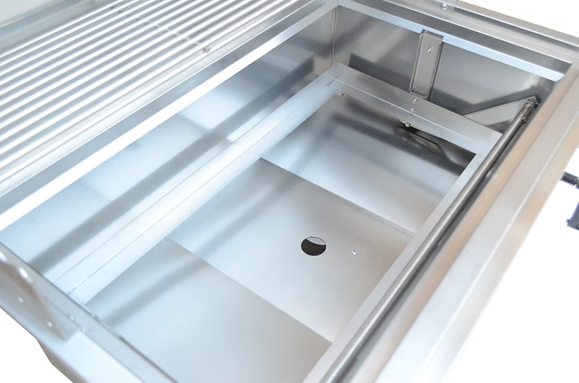 A close-up of the Kokomo Grills 32-Inch Built-In Charcoal Grill by Kokomo Grills, showing its empty stainless steel basin, drain hole, and smooth metal surfaces—an ideal choice for your outdoor kitchen setup.