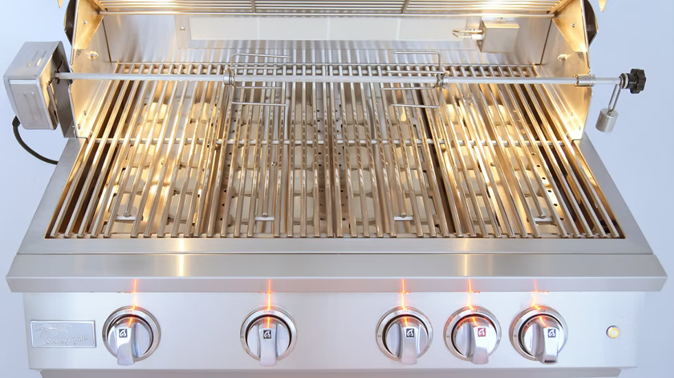 The Kokomo Grills 32-Inch Professional Built-In Gas Grill (4 Burner) features four control knobs, a rotisserie attachment, and glowing interior lights—shown with the lid open and empty stainless steel grates.