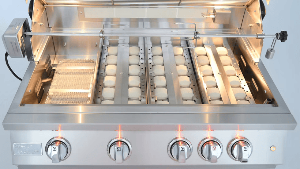 The Kokomo Grills 32-Inch Professional Built-In Gas Grill (4 Burner) features four lit control knobs, an open lid, motorized rotisserie, ceramic briquettes, and removed cooking grates—ideal for any outdoor kitchen.