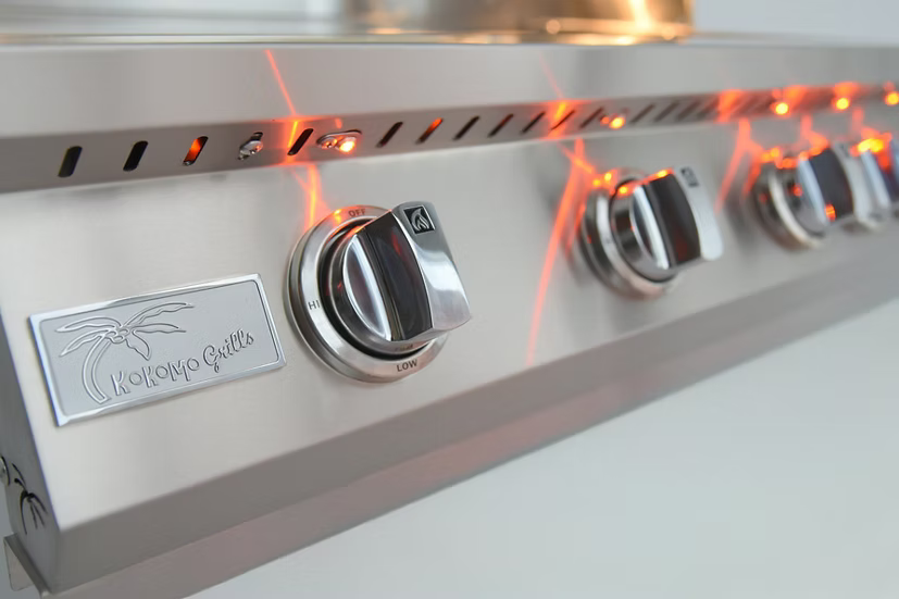 Close-up of the Kokomo Grills 32-Inch Professional Built-In Gas Grill control panel shows four orange LED-lit knobs, highlighting its sleek, modern design—an ideal addition to any outdoor kitchen.