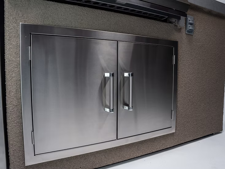 The Kokomo Grills 7-Foot Straight Kitchen Island features a stainless steel double-door cabinet with sleek handles, set in a textured beige wall—ideal for outdoor entertaining and pairs perfectly with other Kokomo Grills products.