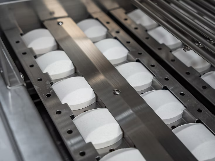 Rows of large white tablets are arranged in a metal tray, similar to how components are neatly organized in compartments for a Kokomo Grills 7-Foot Straight Kitchen Island by Kokomo Grills.