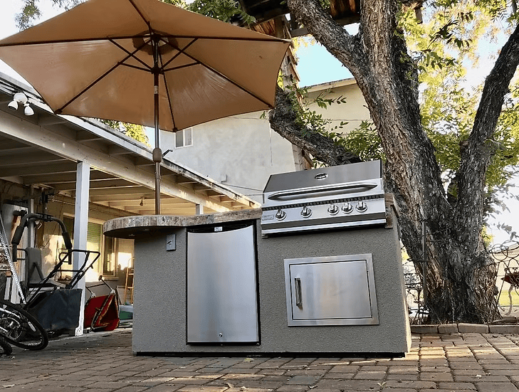 Enjoy the Kokomo Grills Maui 7′6” BBQ Island with a 33” round bar, LED lights, and built-in BBQ—perfect for outdoor gatherings on your patio near your house or garden.