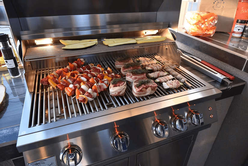 The Kokomo Grills Outdoor Kitchen Montego Model BBQ Island and BBQ Grill lets you cook skewered vegetables, seasoned pork chops, bacon-wrapped treats, and sliced zucchini under bright lights—ideal for any outdoor kitchen or BBQ island.