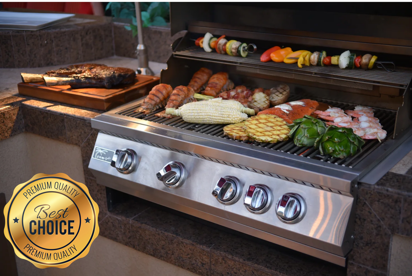The Kokomo Grills 7-Piece Outdoor Kitchen Set features a stainless steel built-in grill loaded with corn, shrimp, chicken, fish, artichoke, pineapple, and veggie skewers. Nearby sits a steak on a cutting board. Premium Quality badge shown.