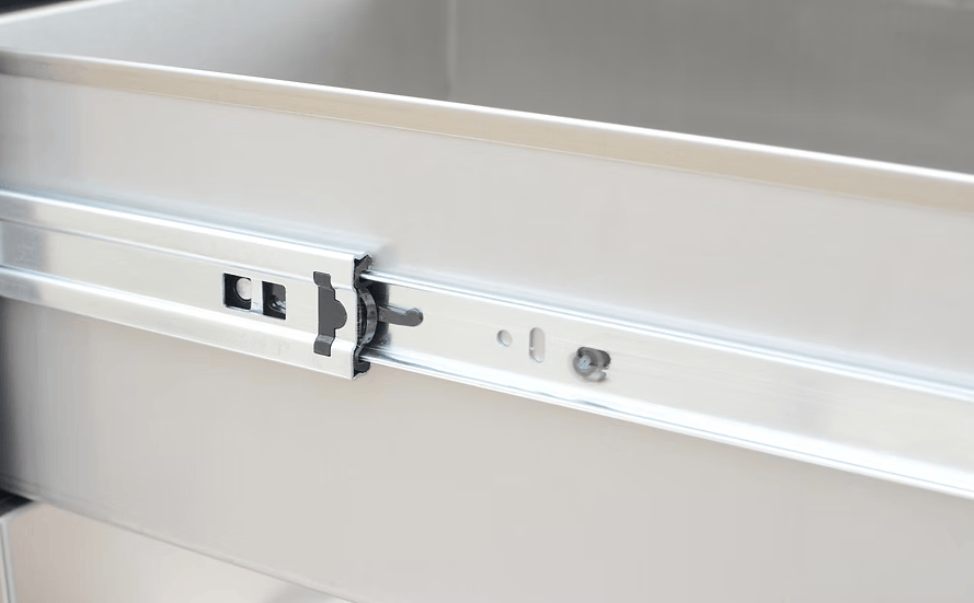 A close-up of the Kokomo Grills Outdoor Kitchen Stainless Steel Triple Drawer KO-TD18 shows its drawer slide mechanism, highlighting the sturdy rail and locking components for smooth operation. Brand: Kokomo Grills.