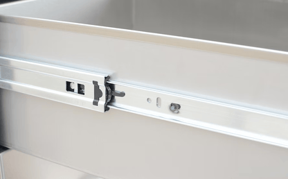 A close-up of the Kokomo Grills Outdoor Kitchen Stainless Steel Triple Drawer KO-TD18 shows its drawer slide mechanism, highlighting the sturdy rail and locking components for smooth operation. Brand: Kokomo Grills.
