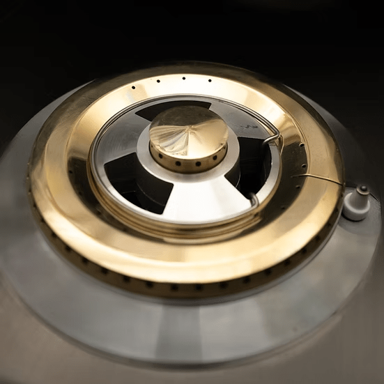 Close-up of the KoKoMo Grills Professional Double Side Burner with Removable Cover by Kokomo Grills, featuring stainless steel and brass accents, central cap, and circular gas outlets—ideal for any outdoor kitchen.