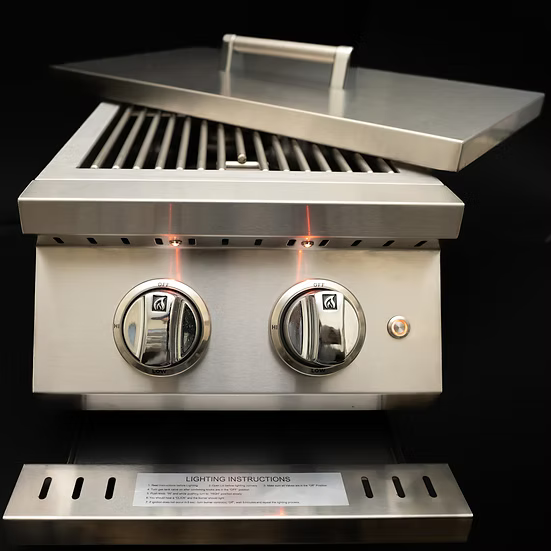 The KoKoMo Grills Professional Double Side Burner with Removable Cover by Kokomo Grills features two control knobs, a partially open lid, and a visible lighting instruction panel, displayed against a black background.