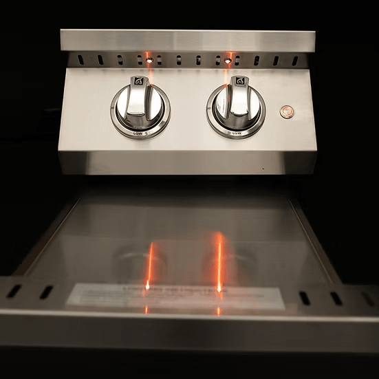 Close-up of the KoKoMo Grills Professional Double Side Burner with removable cover by Kokomo Grills. The stainless steel unit has two control knobs set to low, glowing orange indicator lights, and a clean, reflective surface against a dark background.