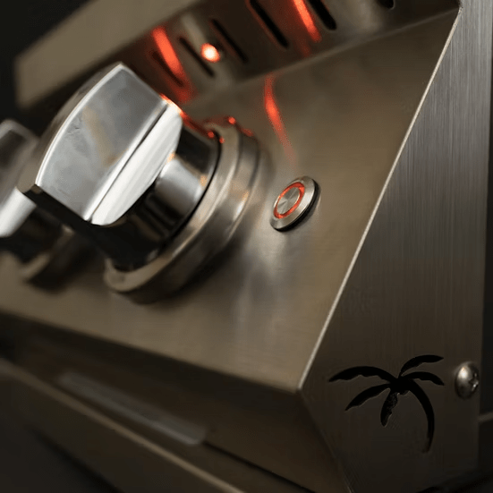 Close-up of the KoKoMo Grills Professional Double Side Burner with Removable Cover by Kokomo Grills—features a metallic control panel with knobs, a round button, red indicator lights, and palm tree cutout design—ideal for any outdoor kitchen.