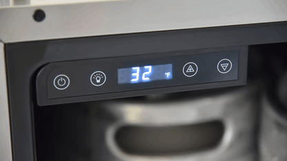 Close-up of the digital control panel on the Kokomo Grills Professional Luxury Outdoor Kitchen Kegerator KO-LUX-KEG, showing 32°F. The sleek stainless steel unit features power, light, and adjustment buttons, with a metal keg visible inside.