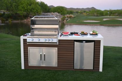 Outdoor kitchen with Kokomo Grills Professional Shiplap Built-In BBQ Island Outdoor Kitchen with Waterfall Edge, stainless steel grill, and mini fridge—set on grass by a pond and golf course, plates of food ready under a clear sky.
