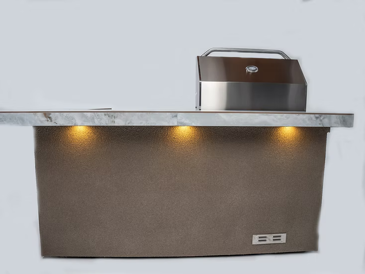 The Kokomo Grills St. John 7-Foot and 6-Inch Kitchen Island by Kokomo Grills features a stainless steel hood, a stone countertop, and three lights that highlight the textured brown base below the counter.