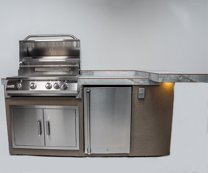 The Kokomo Grills St. John 7-Foot 6-Inch Kitchen Island by Kokomo Grills features a stainless steel grill with four knobs, a built-in mini refrigerator, storage cabinets, and a marble countertop with under-counter lighting.