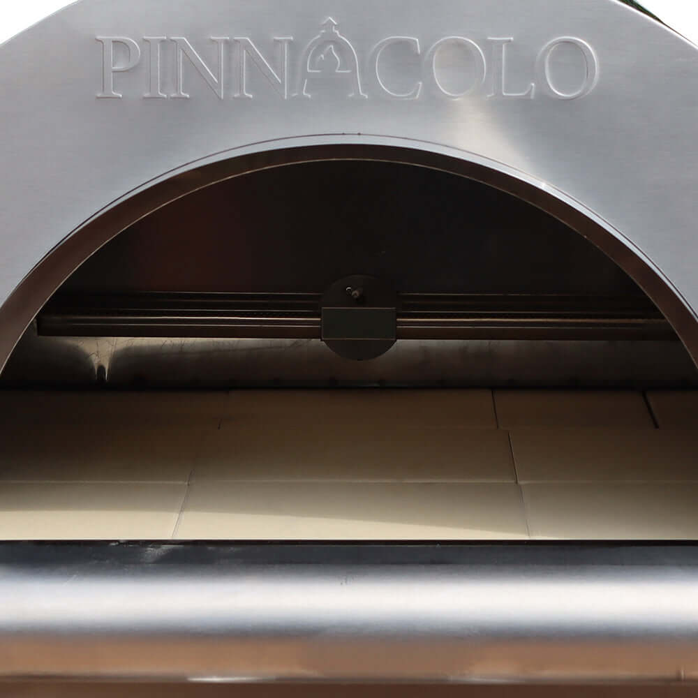 Close-up of a Fire One Up PINNACOLO IBRIDO outdoor pizza oven entrance, showcasing the brand name engraved on the metal arch above the open cooking interior.
