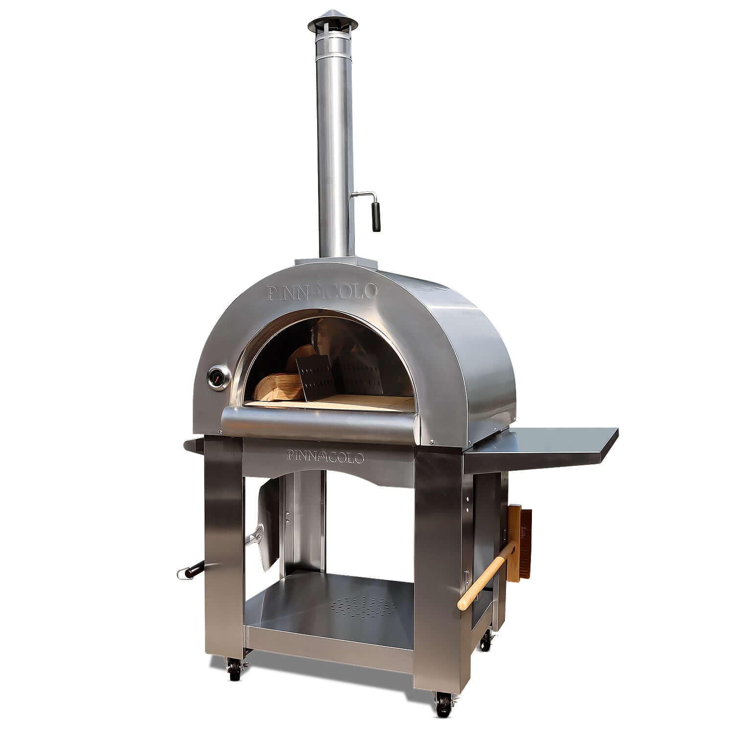 Front-right view of the PINNACOLO PREMIO Wood-Fired Outdoor Pizza Oven, with a side shelf, brush and peel on the lower handles, and the door fully removed, revealing a log of wood and metal separator.