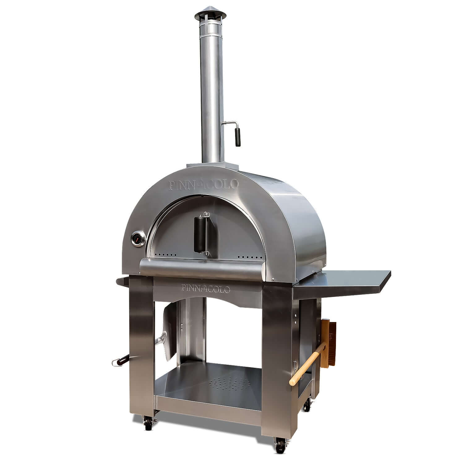 Front-right view of the PINNACOLO PREMIO Wood-Fired Outdoor Pizza Oven, with a side shelf visible and a brush and peel attached to the lower side handles.