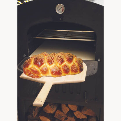 Tuscan Chef Medium Built-In Deluxe Family Pizza Oven (Model GX-CM) without cart – Freshly baked braided bread is being pulled from the oven with a wooden pizza peel.