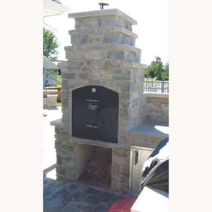 Tuscan Chef Medium Built-In Deluxe Family Pizza Oven without Cart (Model GX-CM) – Showcasing the unit enclosed in a tall white stone shell with a firewood storage compartment below, located on a patio.