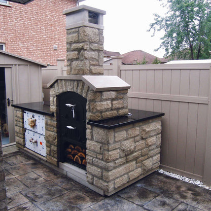 Tuscan Chef Medium Built-In Deluxe Family Pizza Oven (Model GX-CM) – Installed in a stone enclosure with a black countertop in the backyard.