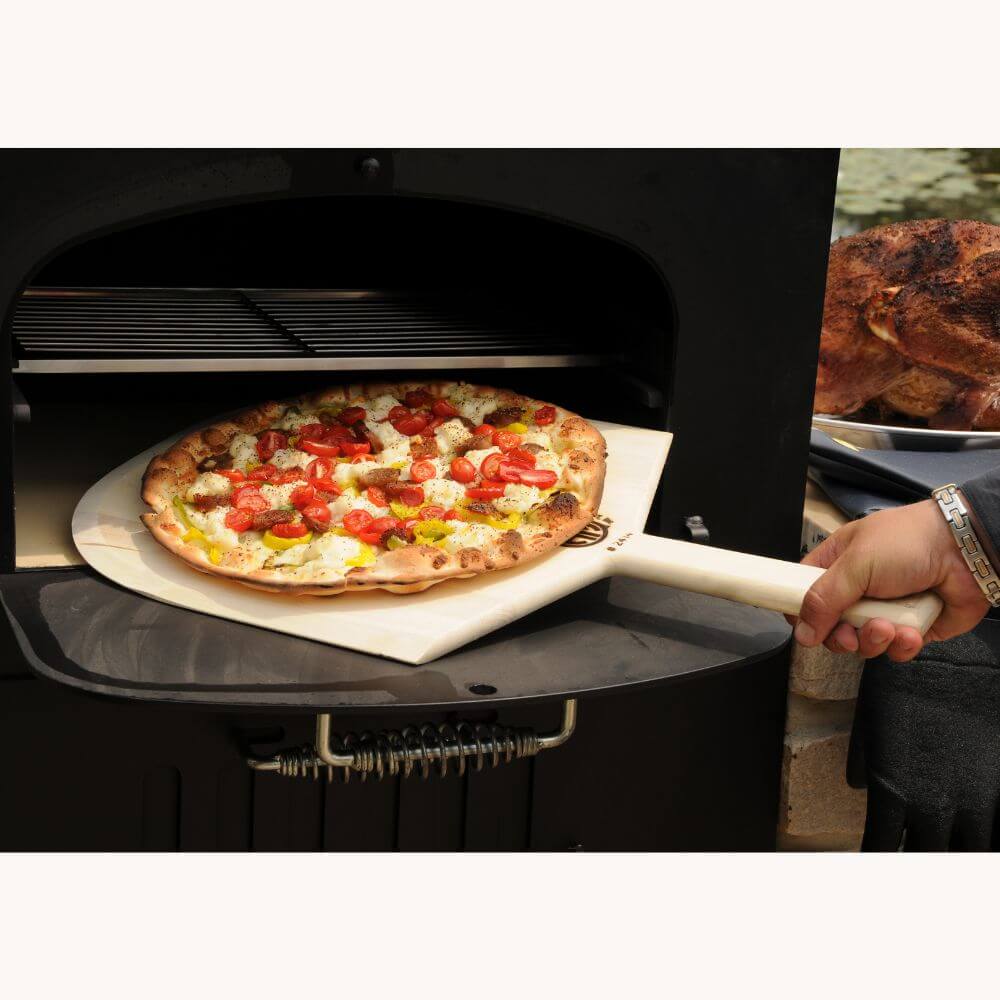 Tuscan Chef Medium Built-In Deluxe Family Pizza Oven (Model GX-CM) without cart – A vegetable loaded pizza is being pulled from the oven with a wooden pizza peel.